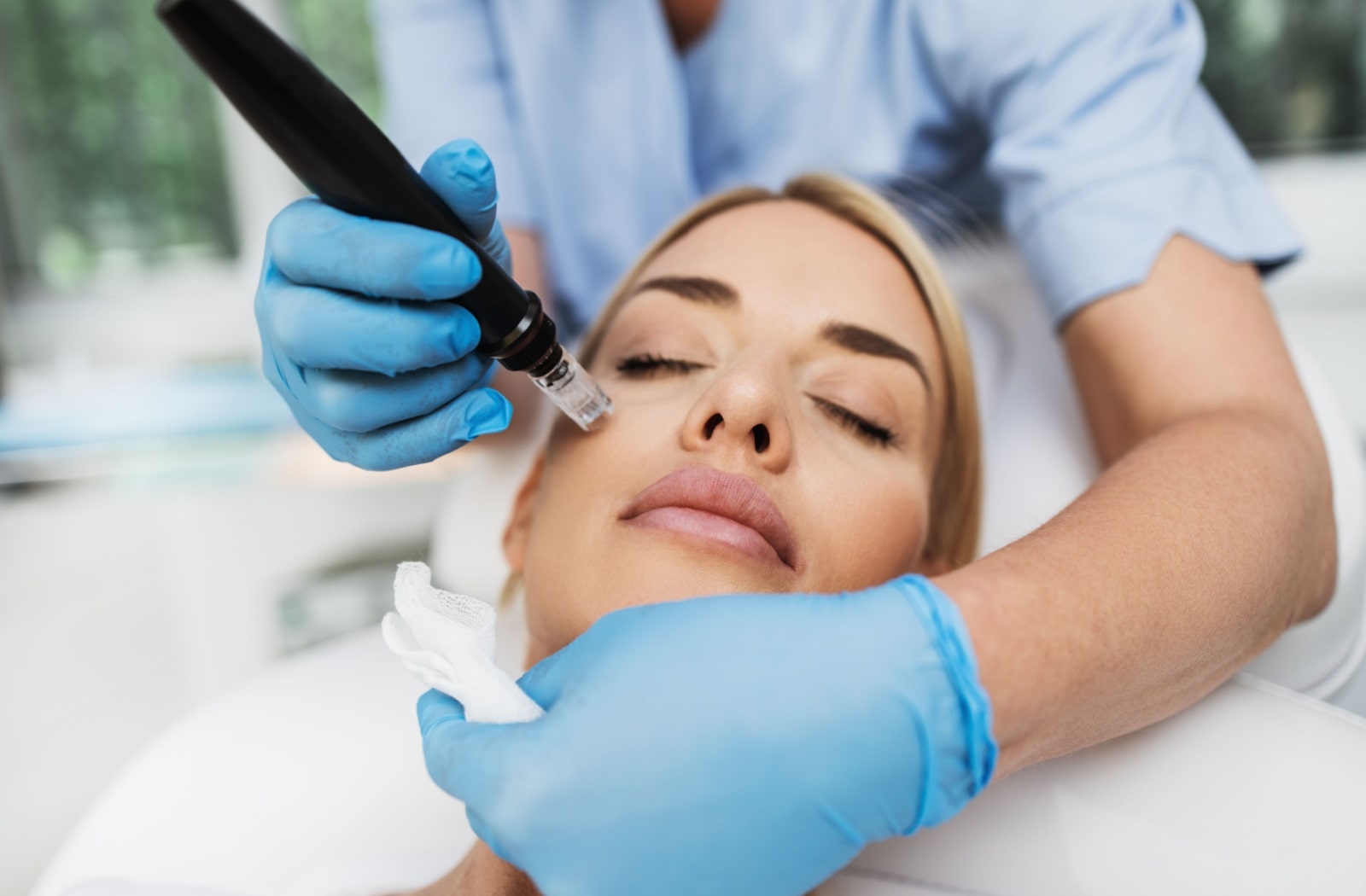 A woman receiving microneedling treatment from a professional esthetician