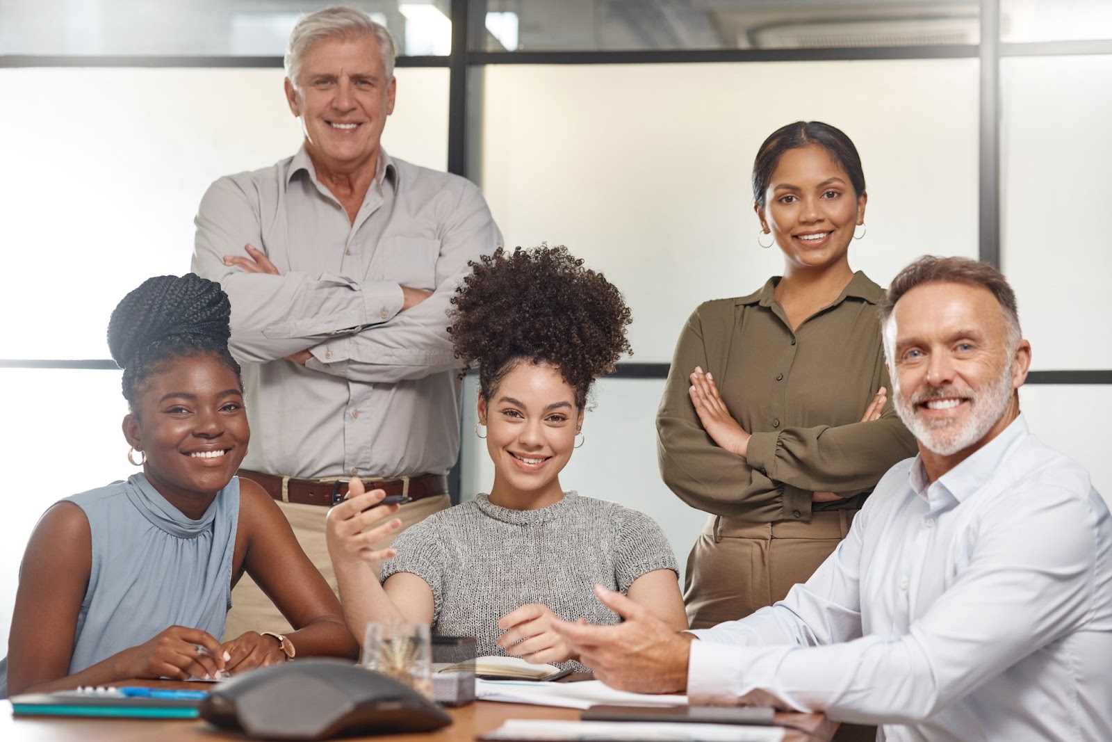 A group of financial consultants cheerfully pose for the camera after discussing beneficial ownership compliance in a bright, professional office setting.