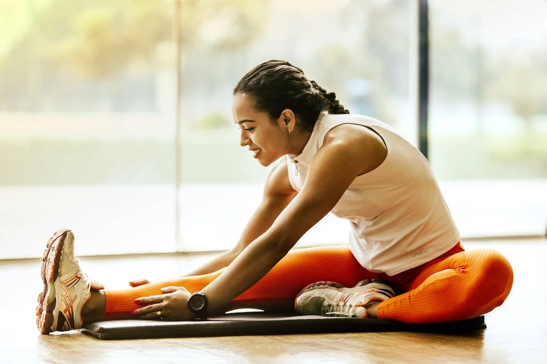 oman in orange leggings stretching on yoga mat