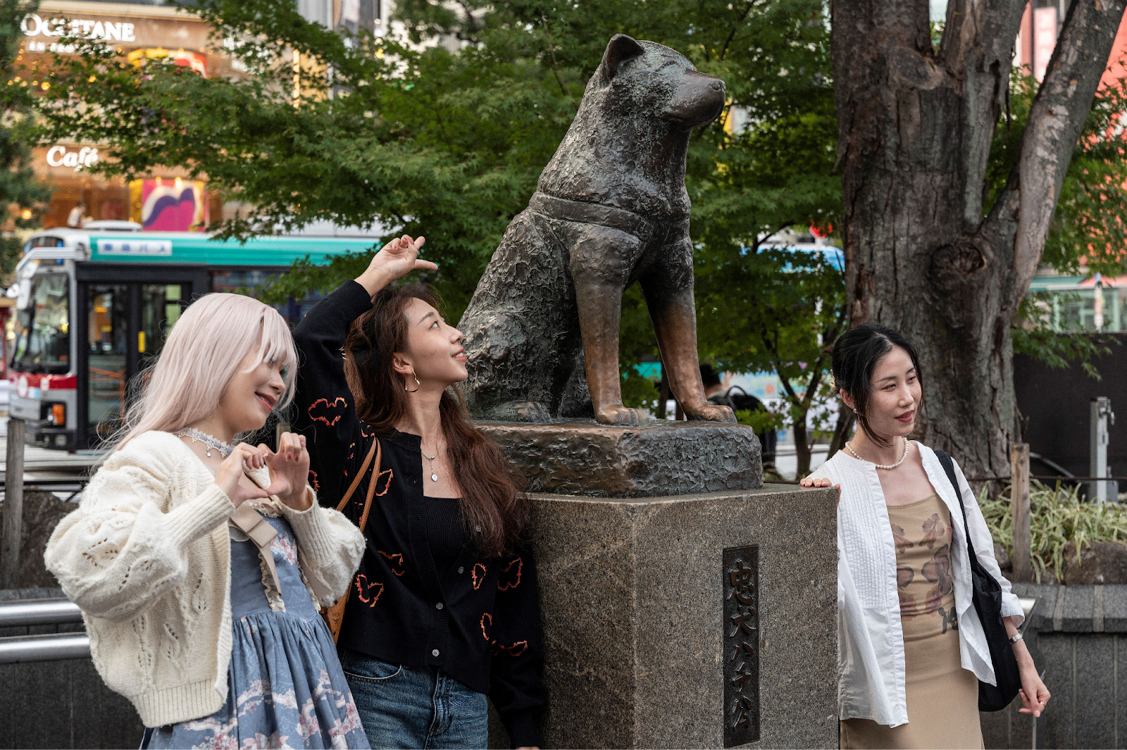 La estatua de Hachiko en la estación de trenes de Shibuya junto a unas turistas que posan junto a ella.