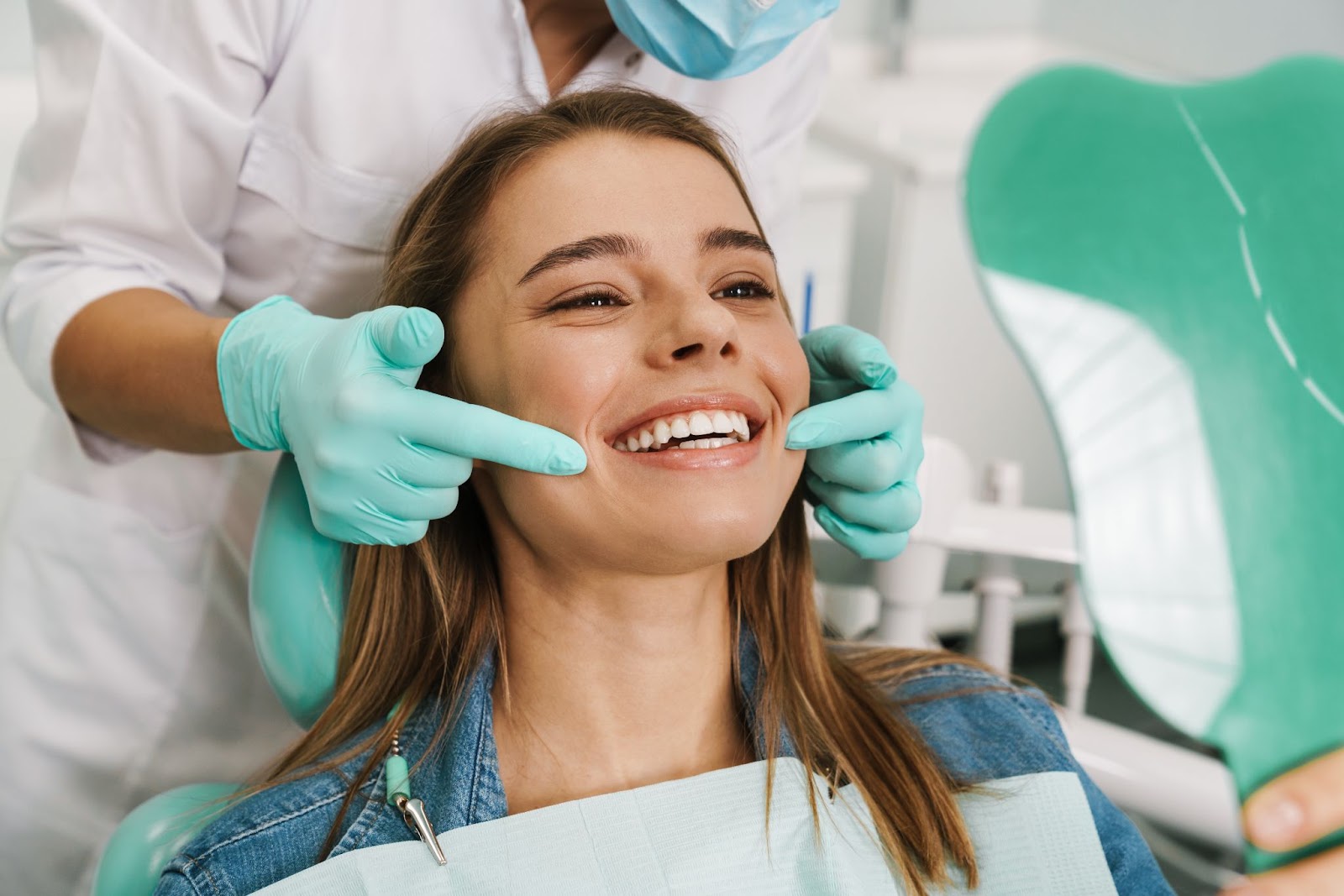 A woman in a dentist chair smiling as she looks in the mirror after her filling procedure.