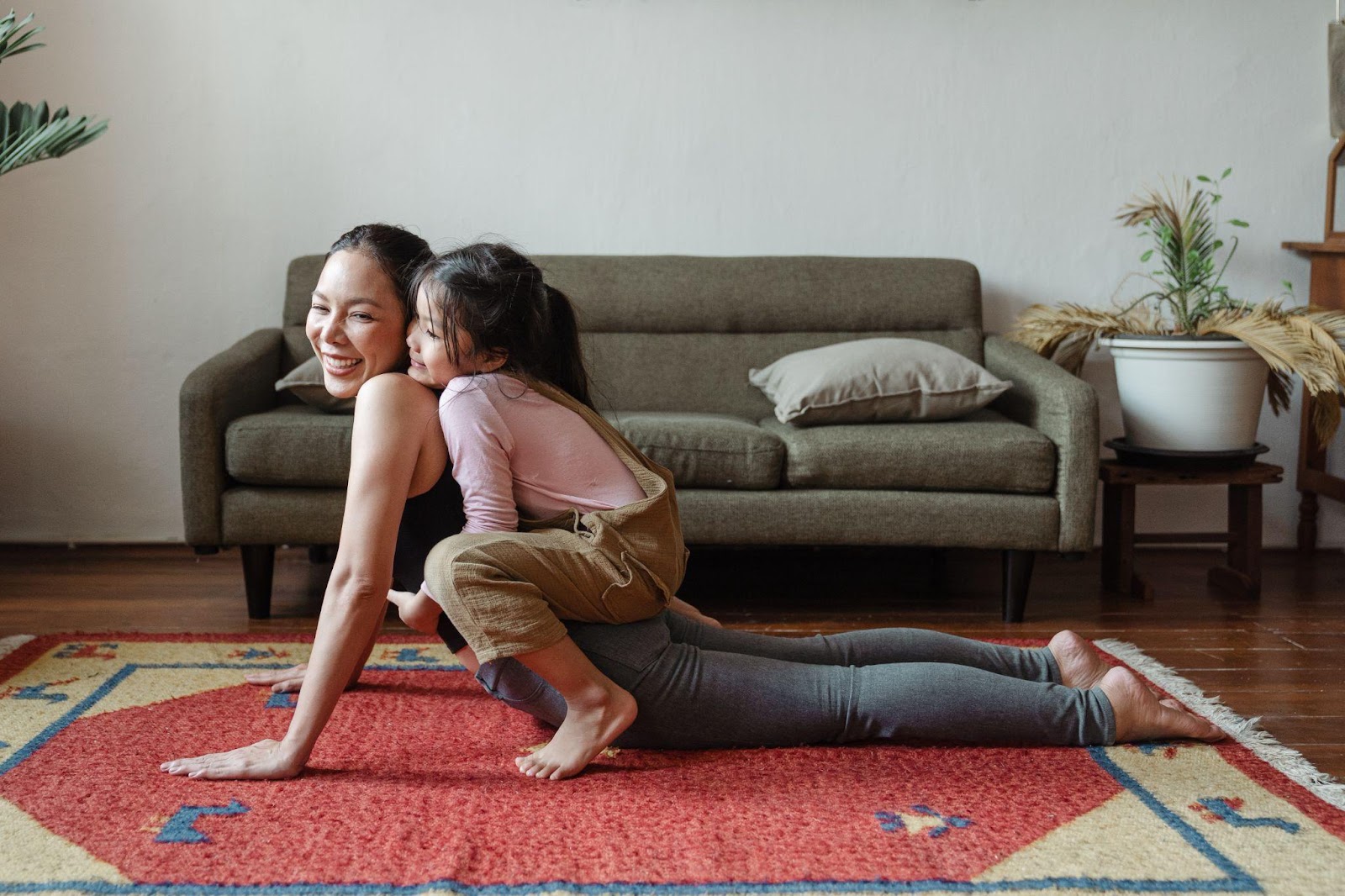 Girl hugging her mom while doing yoga poses.
