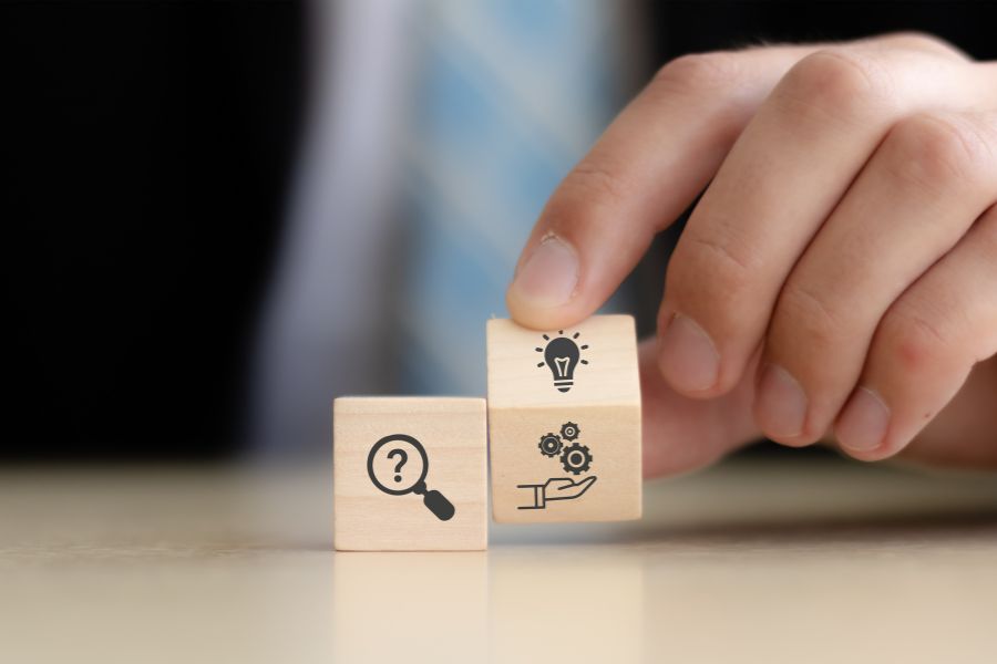 Person holding wooden block with magnifying glass and bug icon.