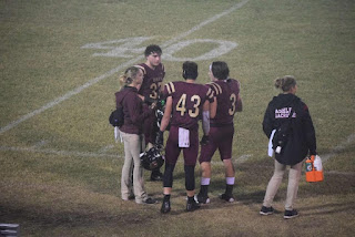 A group of people in maroon uniforms on a football field

Description automatically generated