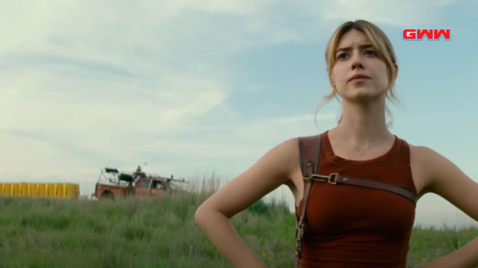 Kate Cooper in a field, looking determined, with a vehicle behind.