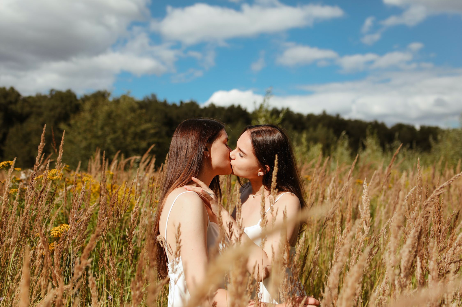 Two women kissing each other in a field