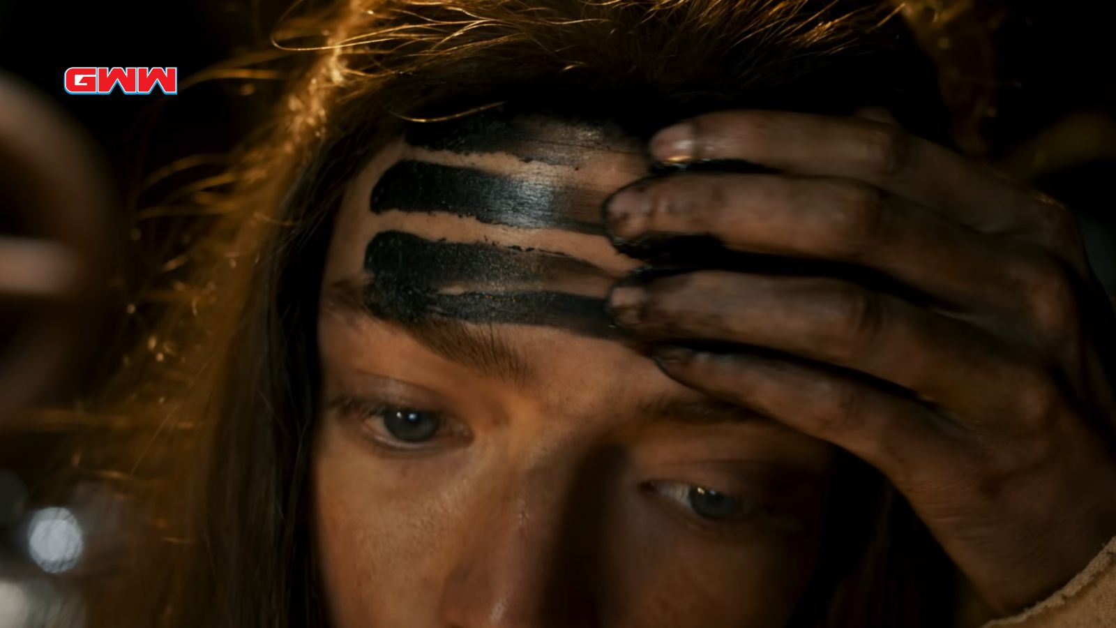Close-up of a woman with black stripes on her forehead.