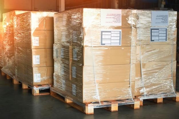 Cajas de embalaje envueltos en plástico apilados en tarimas almacén de almacenamiento almacén de suministros de envío