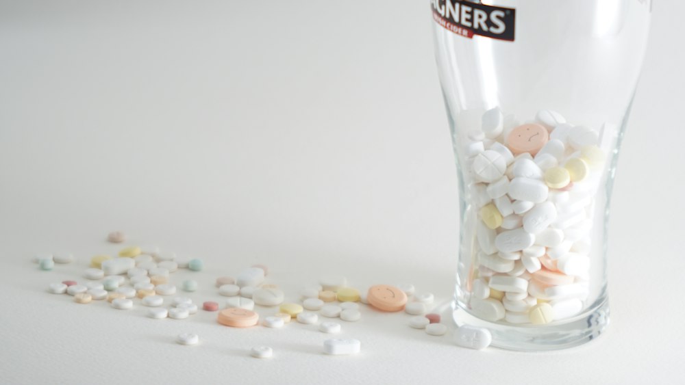 assorted medication pills in clear highball glass