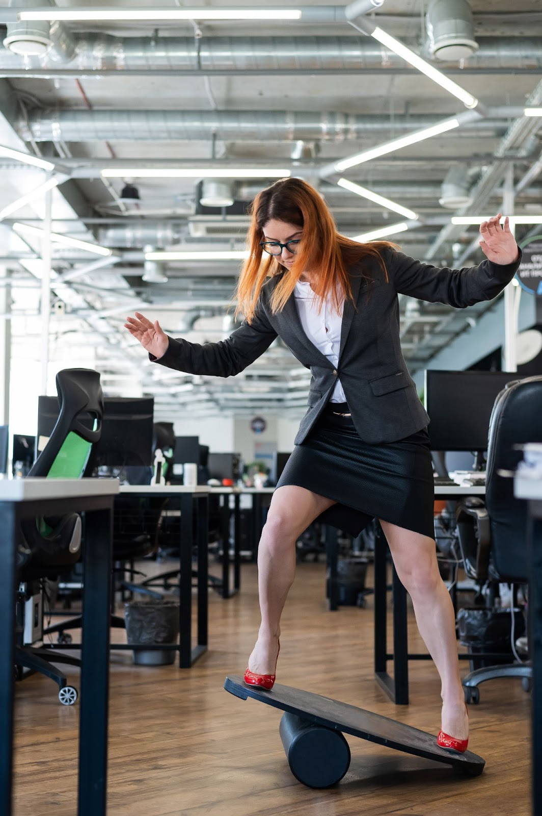 Business woman learning to use a standing desk balance board. 