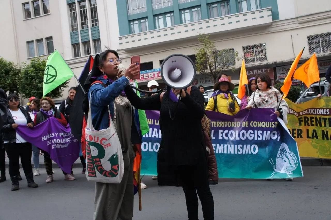 A rebel uses her phone and a megaphone to give a speech on the street