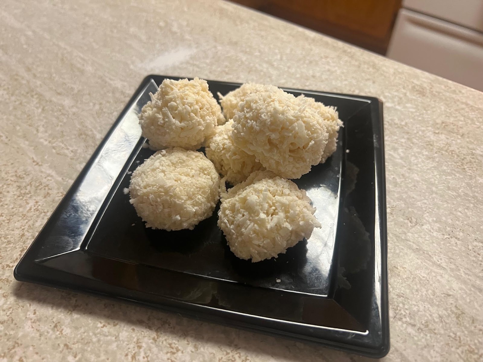 A plate of coconut balls on a counter

Description automatically generated