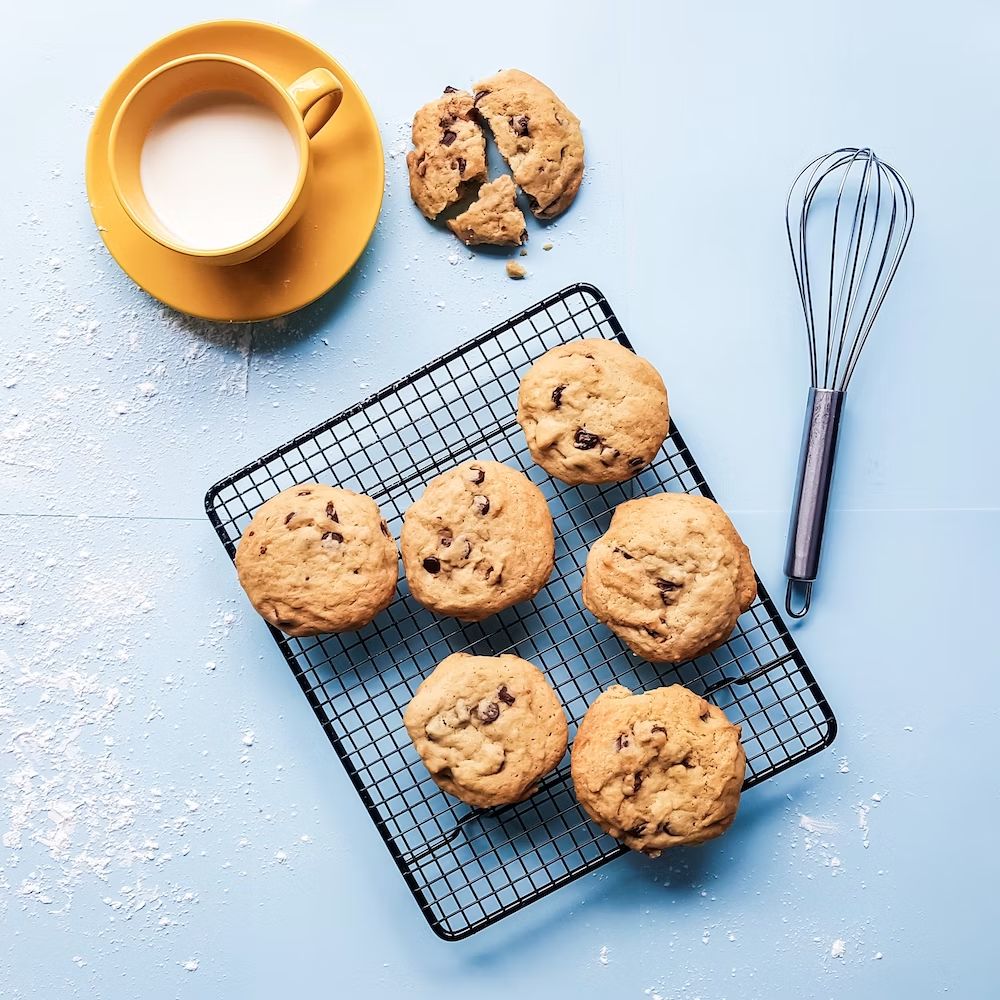 Cookies On a Cooling Rack With a Whisk and Milk Cup on The Side