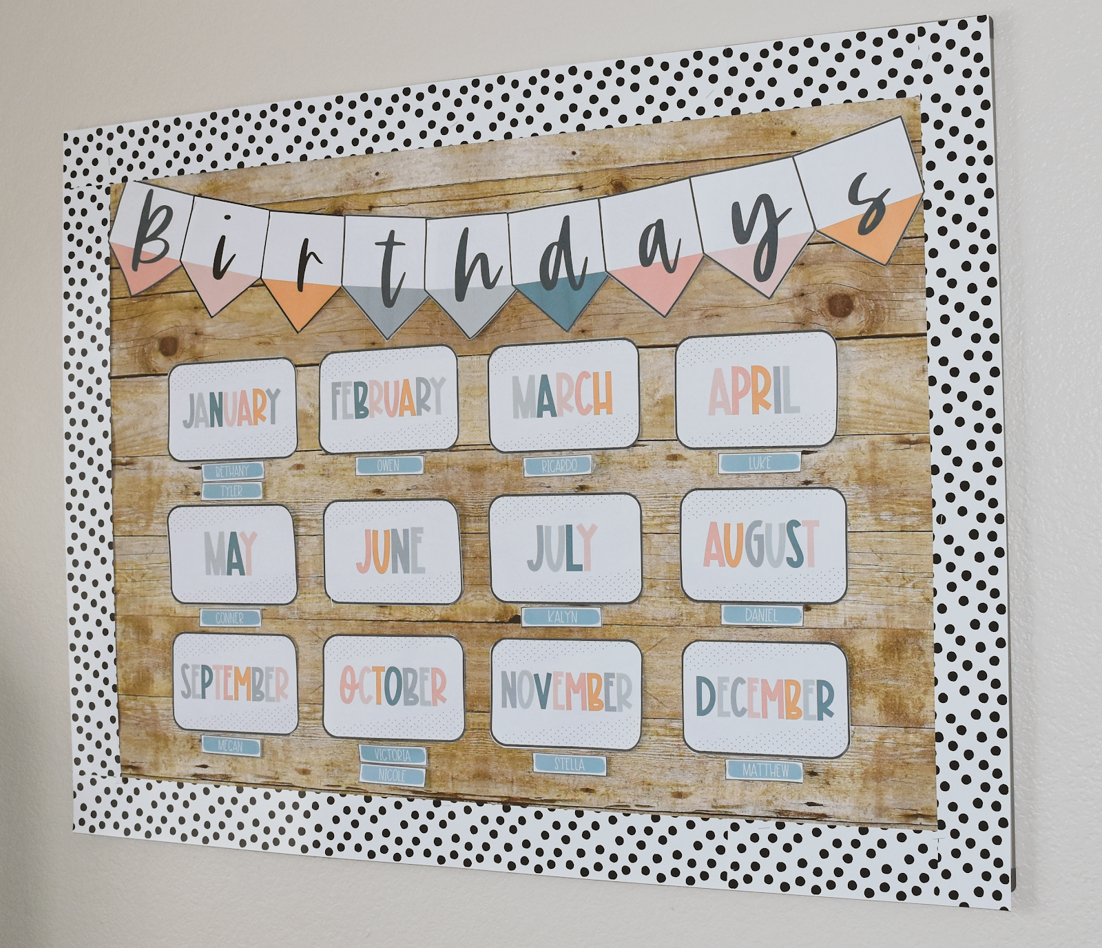 This image shows a bulletin board display with a heading reading "Birthdays". There is a card for each month of the year with smaller cards for student names underneath. The letters on the month cards are in calm colors. 