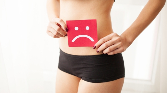 woman with a urinary tract infection holding a picture of a sad red stick figure