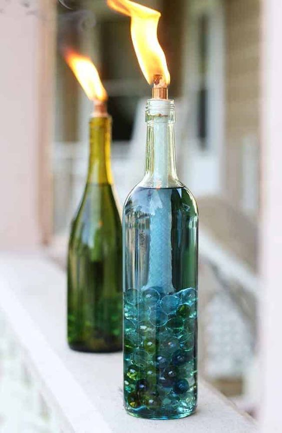 weathered tiki torches with beautiful, colorful DIY wine bottle