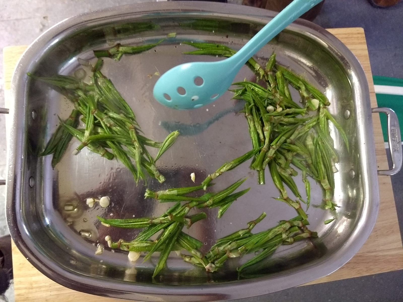 A spoon in a bowl of green vegetables  Description automatically generated