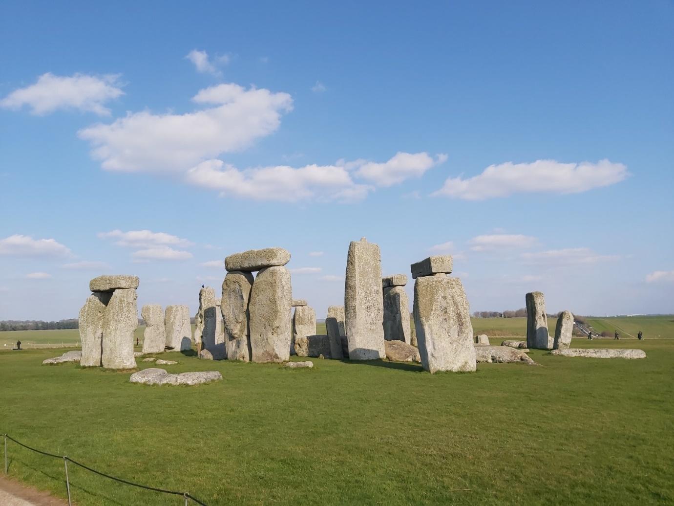 A stonehenge in a grassy field with Stonehenge in the background

Description automatically generated