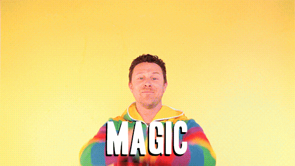A GIF of a man dressed in a vibrant rainbow hoodie drawing a rainbow with his hands that says 'magic'.