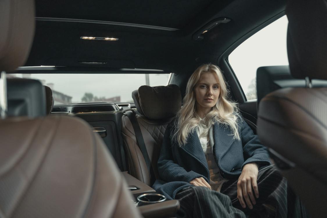 Free Woman in Blue Coat Sitting on Back Seat of a Car Stock Photo