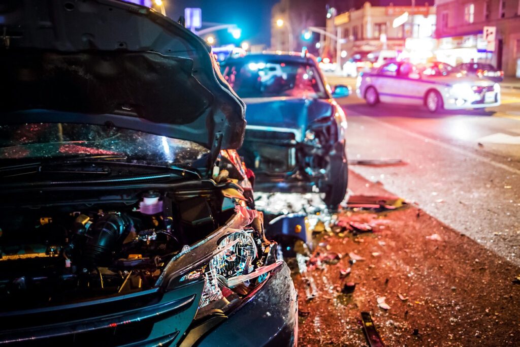 Two car crash at night with police car in background. Our Houston car accident lawyers defend those injured in car crashes. 