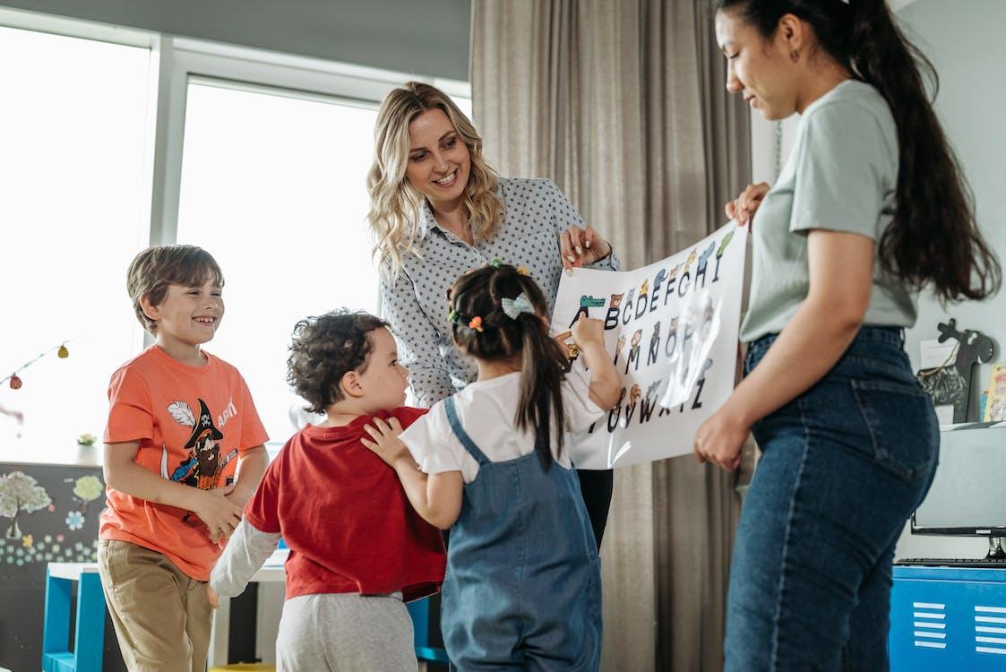 Free Teachers Holding a Poster of the Alphabets Stock Photo