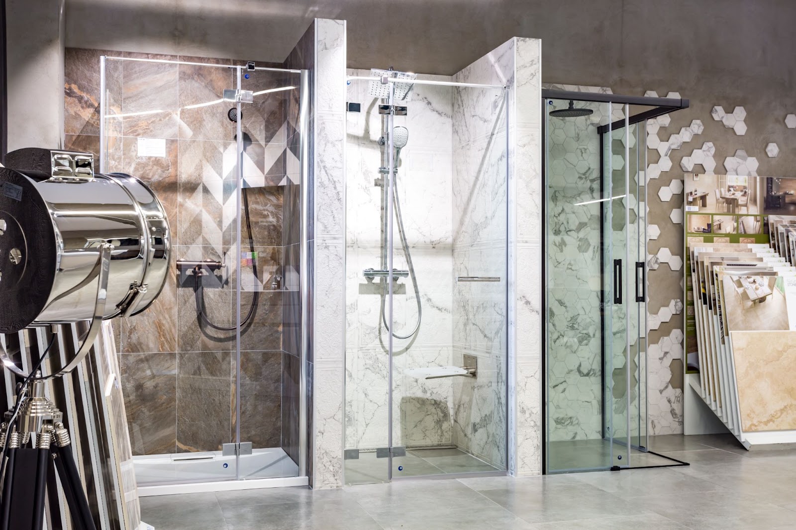 Shower cabin display inside a luxurious showroom featuring high-end plumbing fixtures; a spotlight and stacks of bathroom tiles are visible on the sides. 