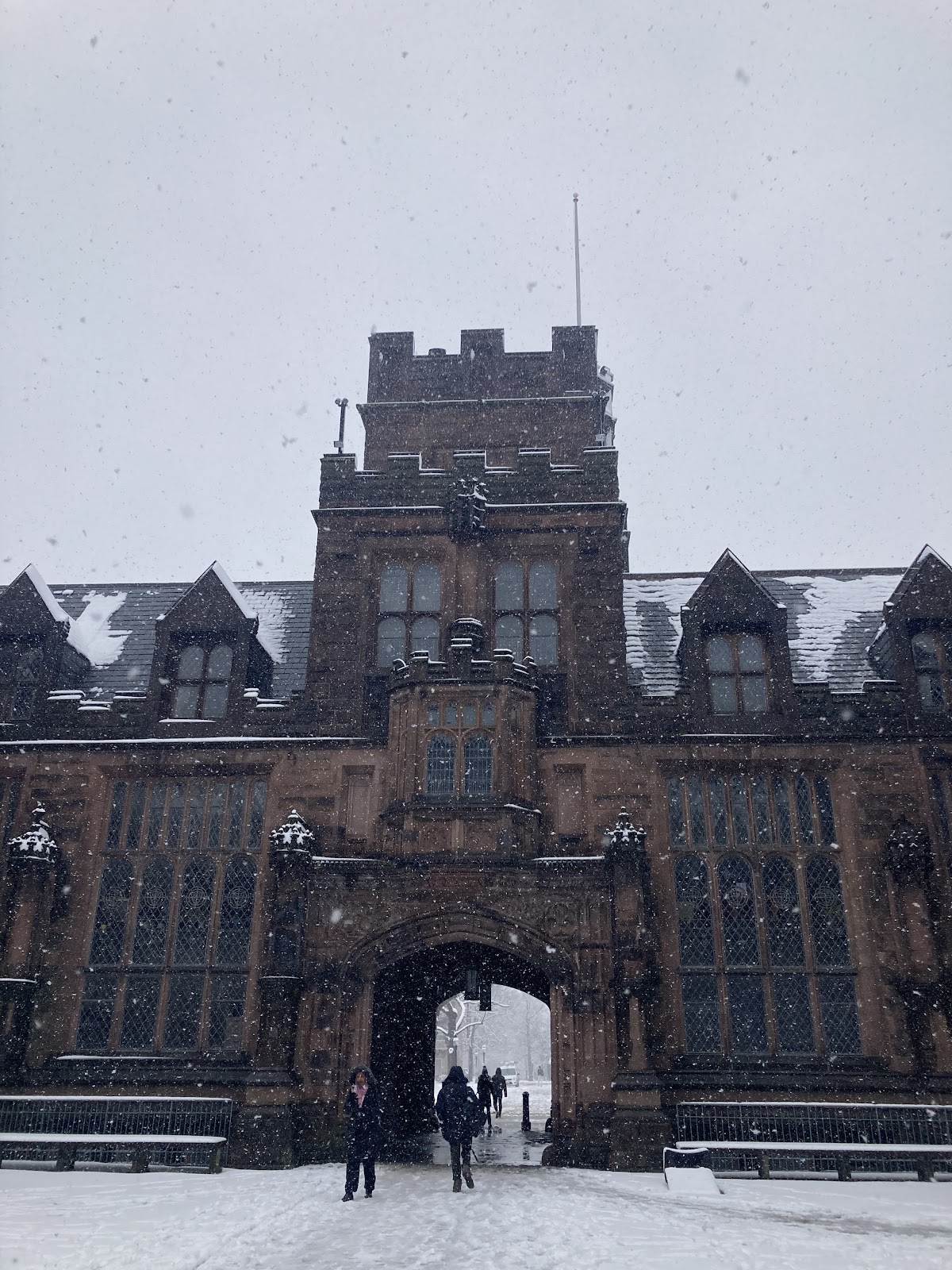 Snow covers the ground and flurries from the sky outside East Pyne Hall
