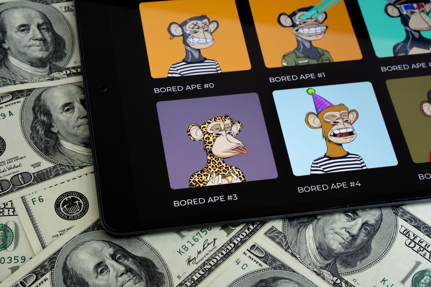 Una colección de Bored Apes en un ipad sobre billetes de dólar estadounidense