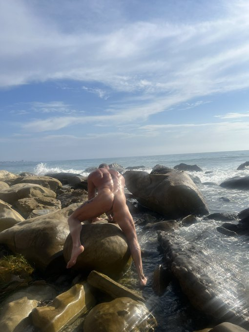 Matthew Figata posing on a rocky beach naked showing off his tanned muscle body