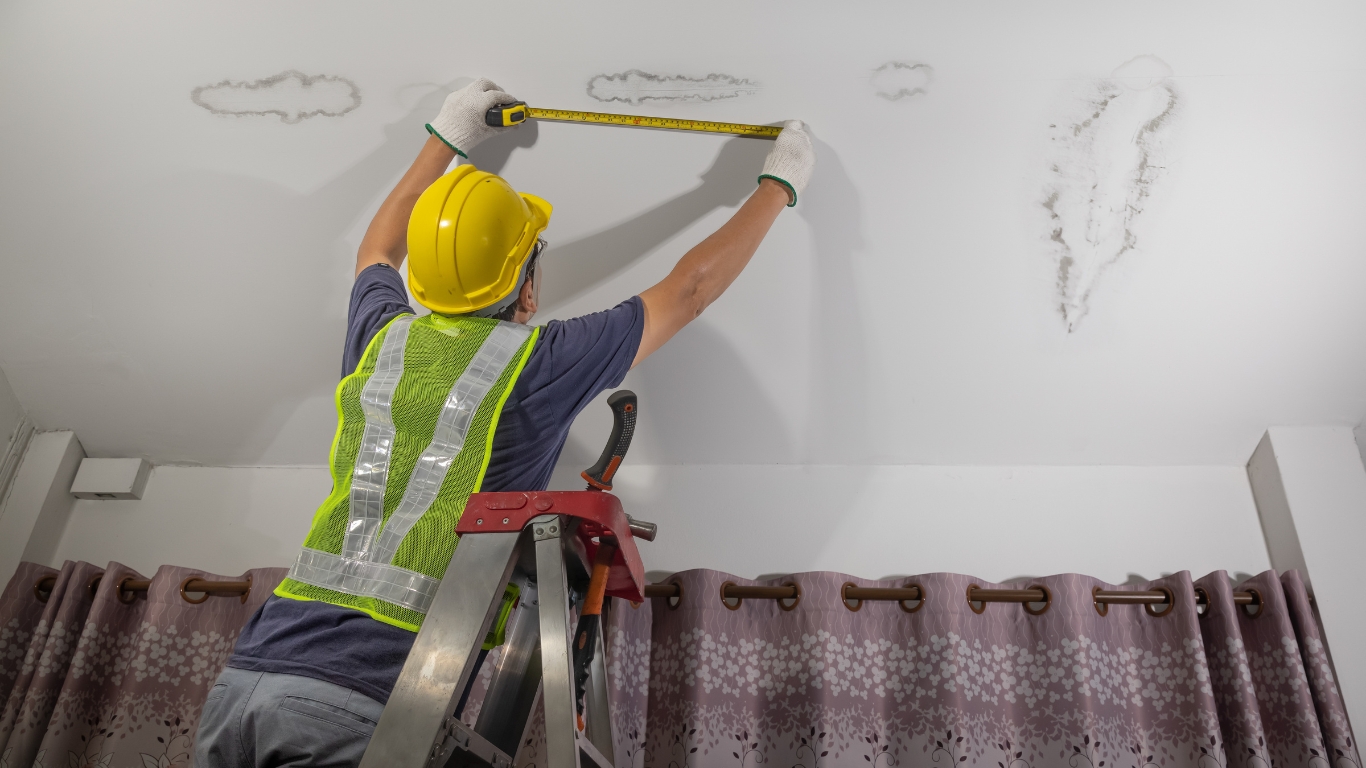 Plumber measuring wall with tape measure