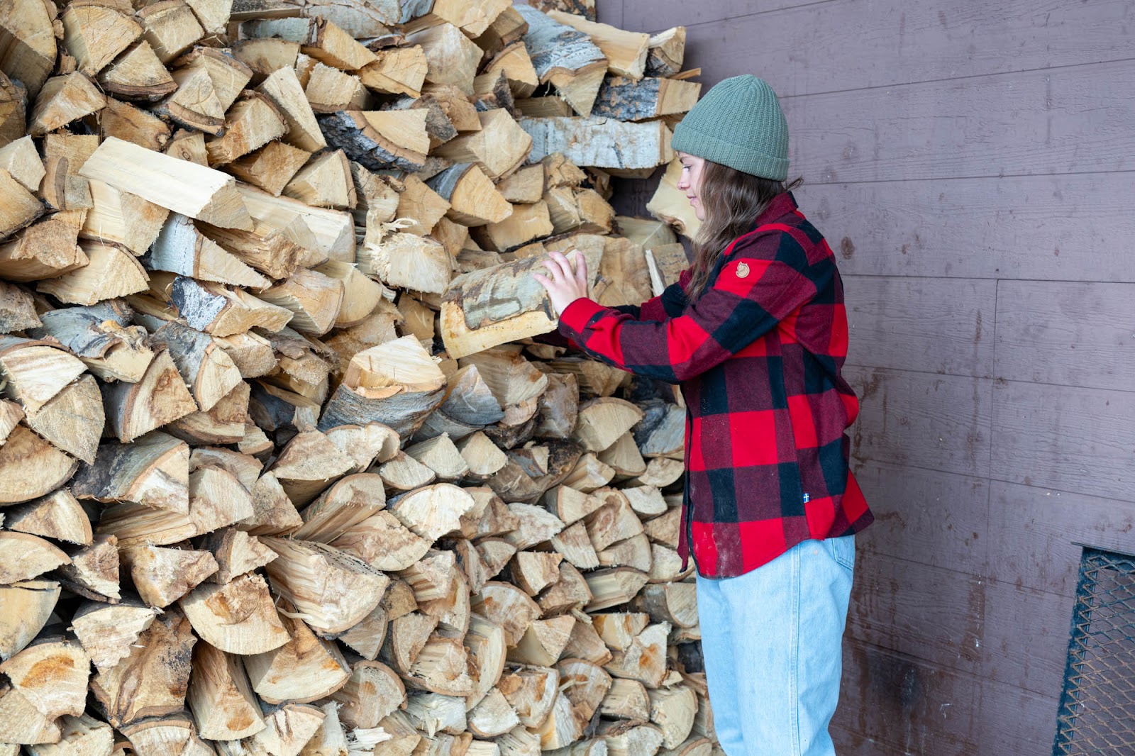 woman stacking wood in long-sleeve shirt
