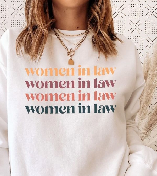 mujer con una sudadera con capucha blanca con un estampado de "mujeres en la ley"