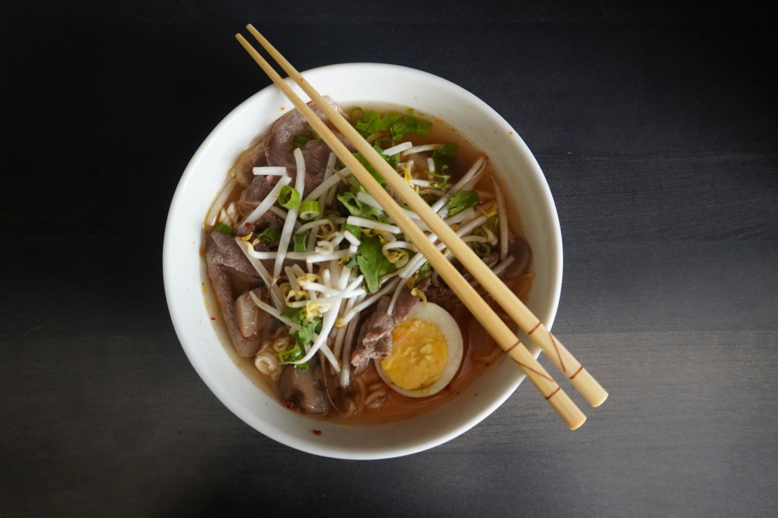 A savoring steaming bowl of ramen, a beloved comfort food that warms the soul with its rich broth and springy noodles.