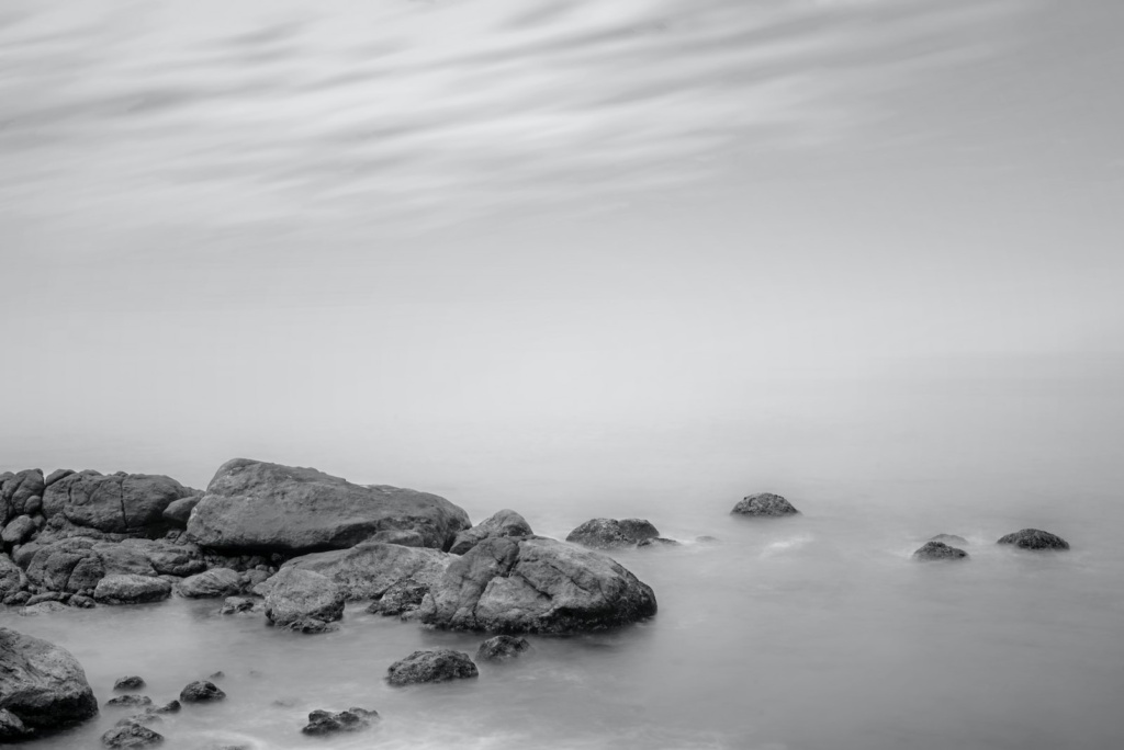 rocks beside body of water grayscale photography