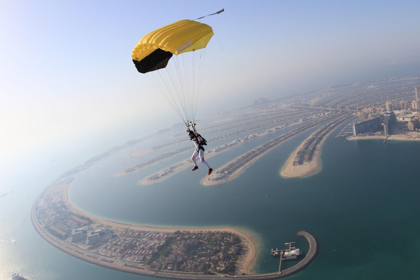 A person skydiving with a yellow parachute

Description automatically generated
