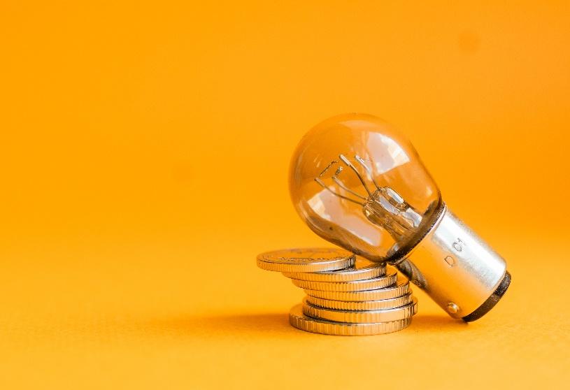 A light bulb on top of a stack of coins

Description automatically generated