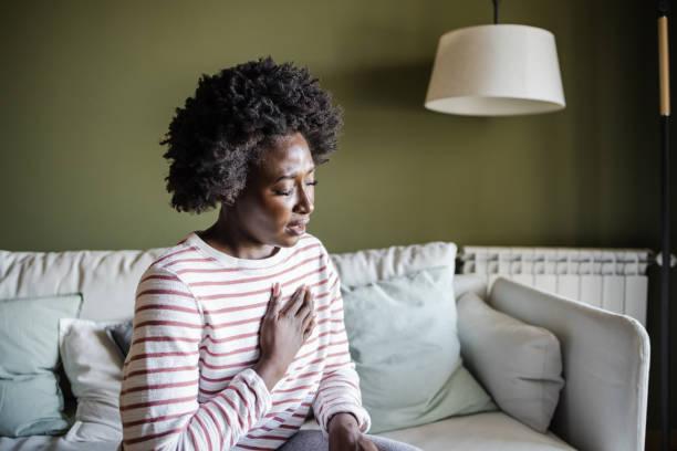 a young woman is having chest pains - black woman stress stock pictures, royalty-free photos & images