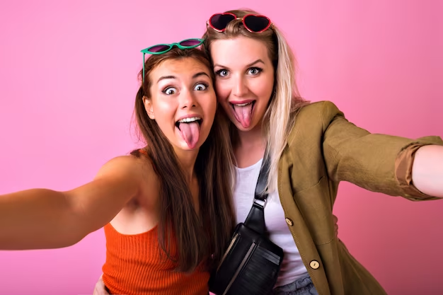 two girls sticking their tongue out and taking a selfie