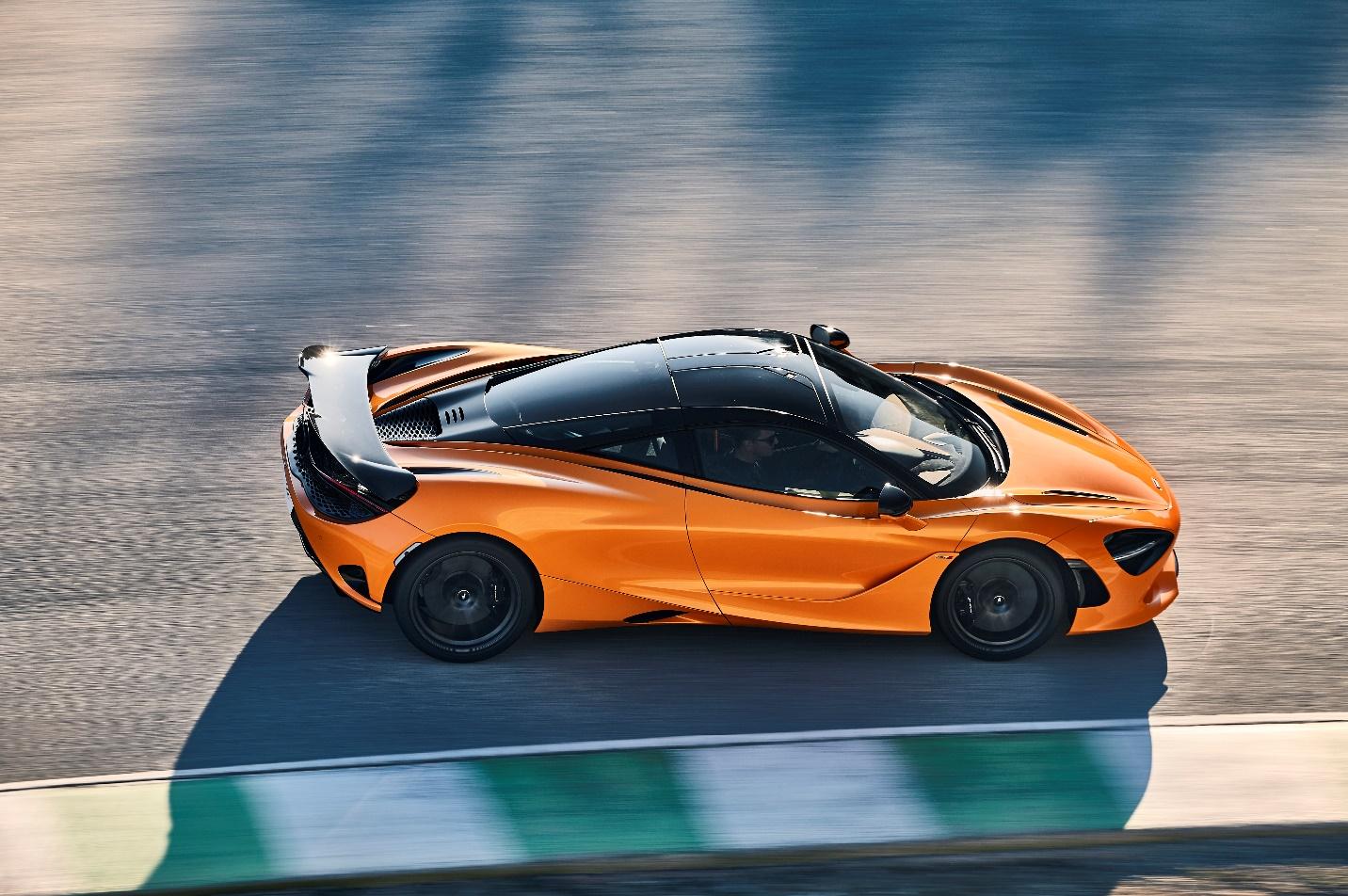 An orange sports car on a road

Description automatically generated