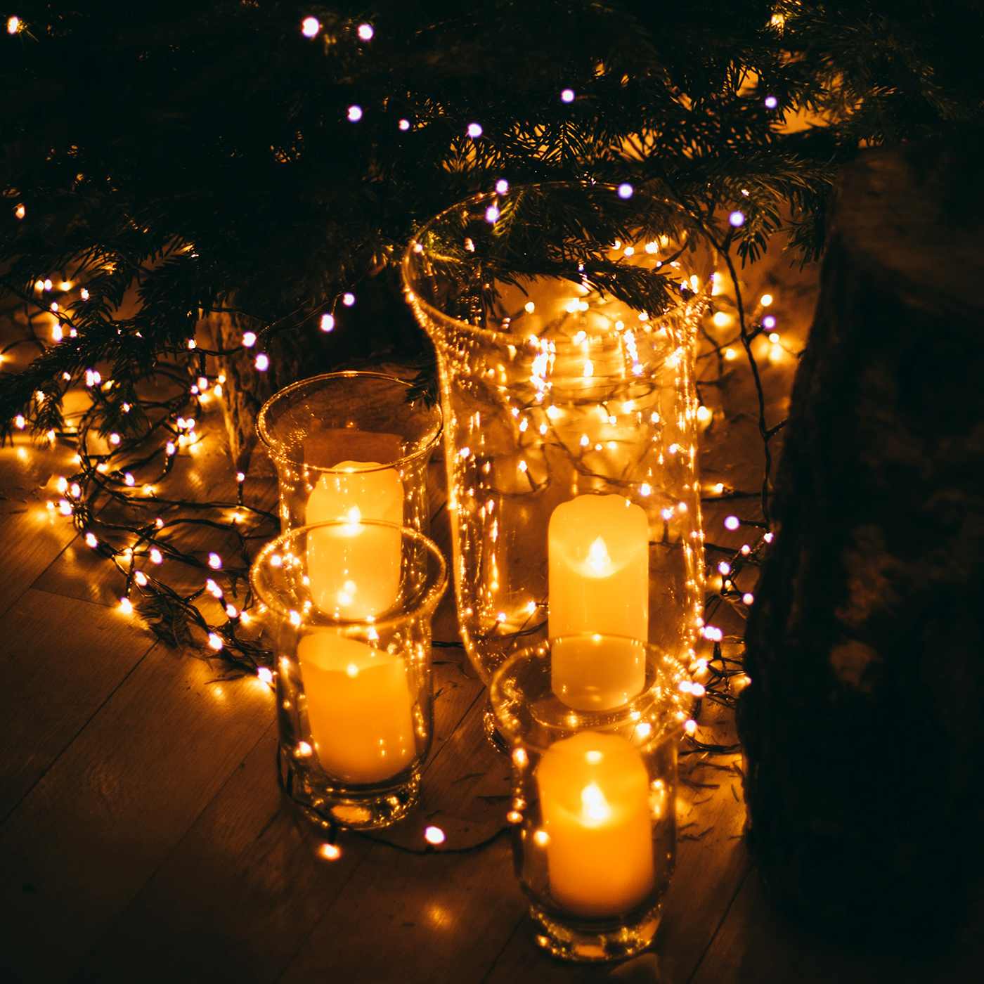 candle lanterns and fairy lights under a Christmas tree