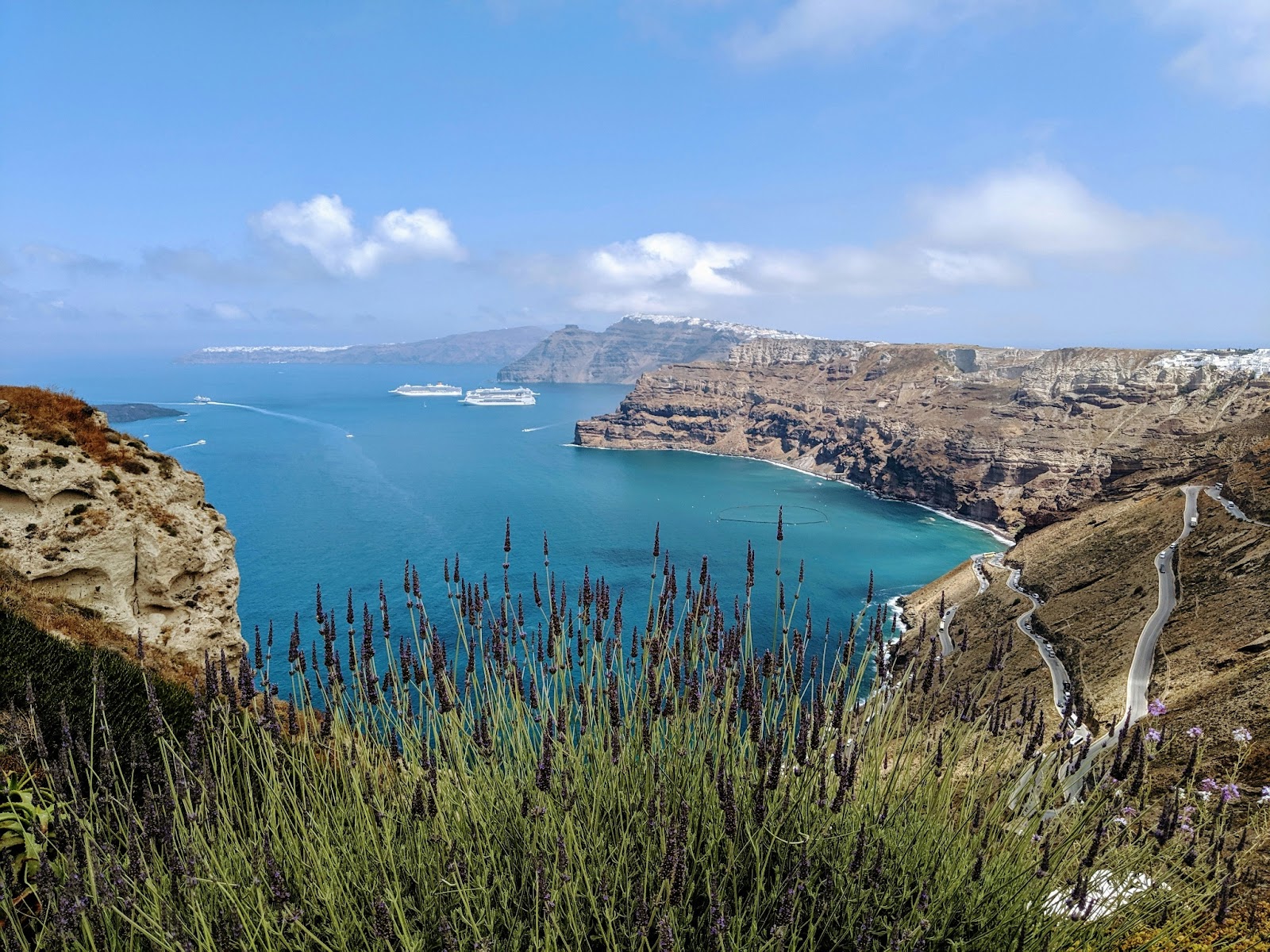 Hikers trekking along Santorini's rugged coastline with views of the caldera.