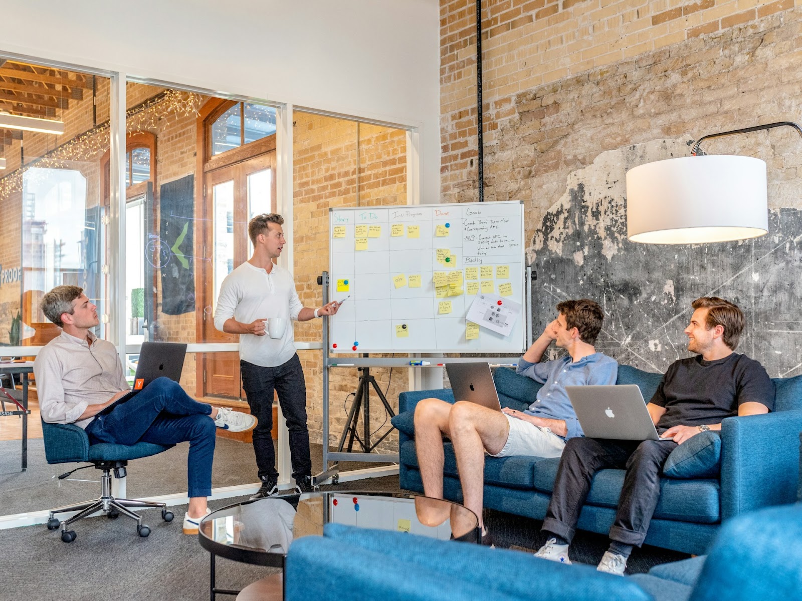 People sitting around a table with a whiteboard, brainstorming ideas.