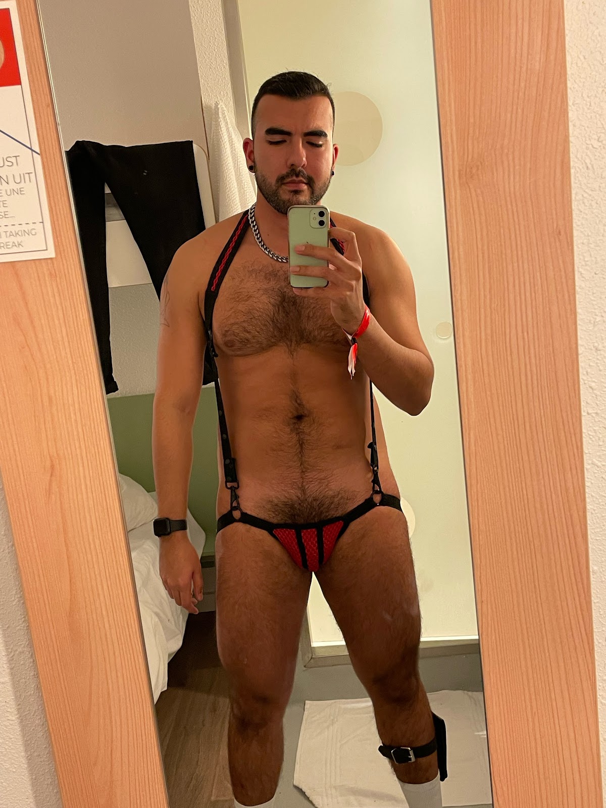 onlyfans gay content creator Phil wearing leather jock strap fetish suit with suspenders and wallet ankle harness and athletic socks taking an iphone mirror selfie