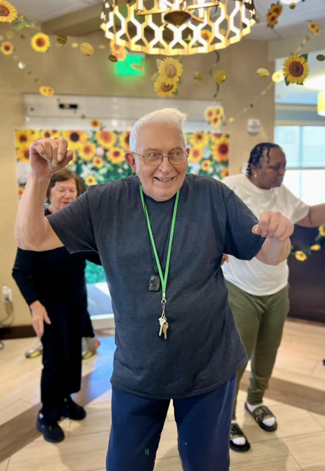 A senior smiling and dancing with his hands in the air