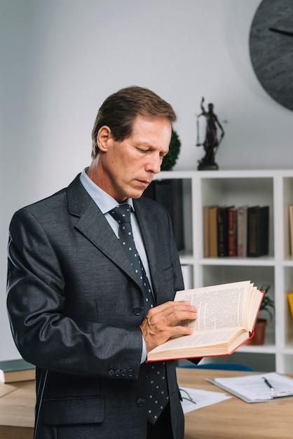 Free photo serious mature lawyer reading law book in the courtroom