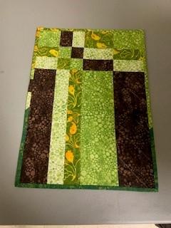 A green and brown patchwork rug

Description automatically generated