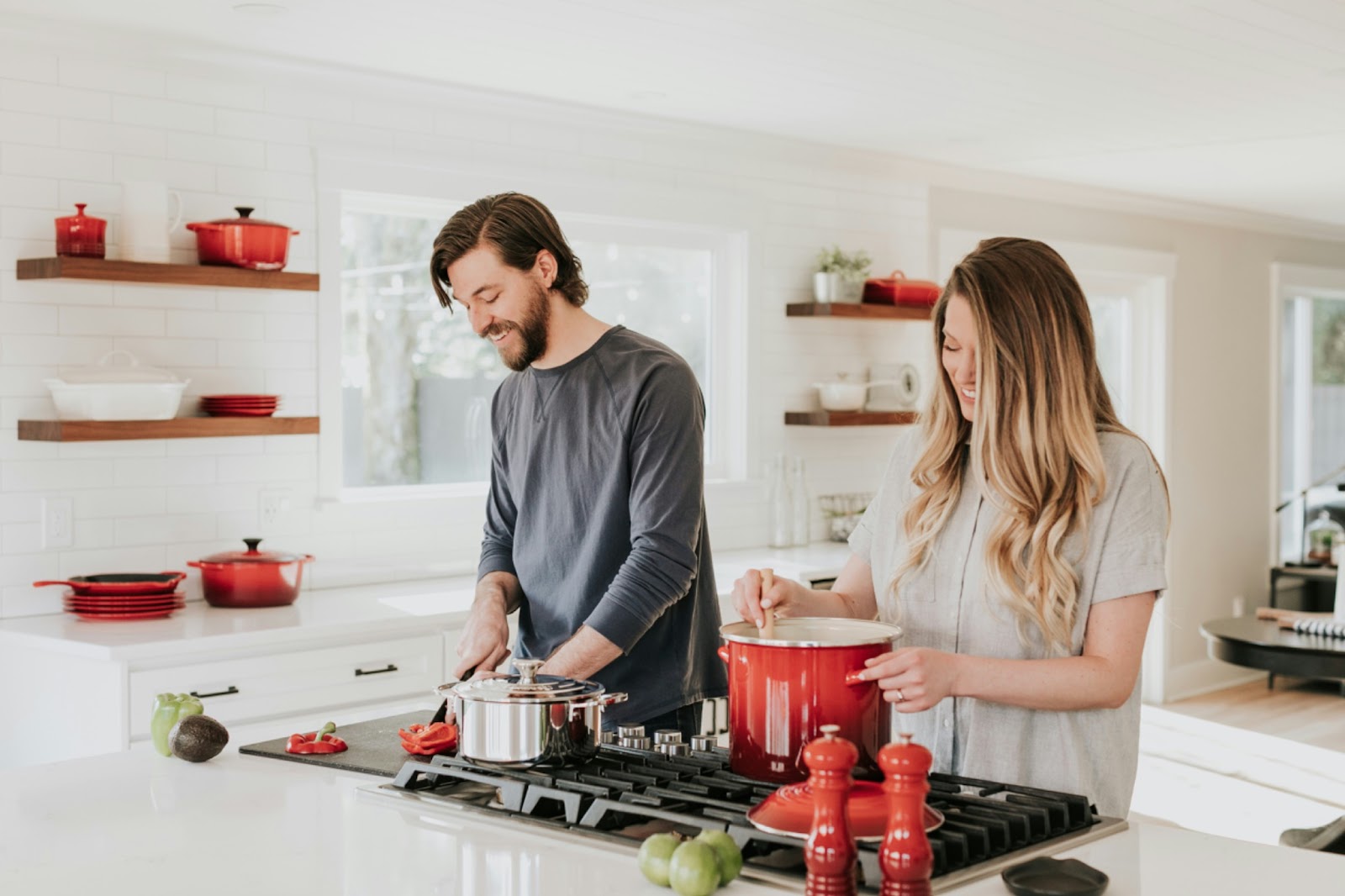 woman and man balancing their relationship in kitchen smiling making food on stove