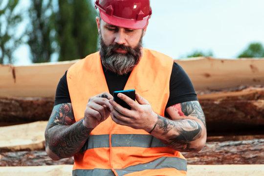 Worker in overalls and with a tattoo are checking the quality of materials  and other inspections, makes recording on your mobile phone Stock Photo |  Adobe Stock