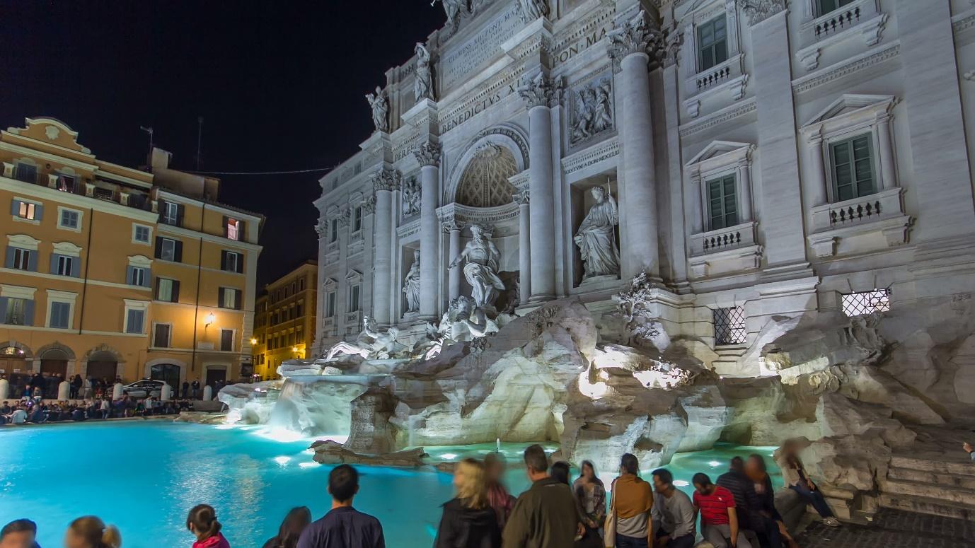 A group of people standing around a fountain

Description automatically generated